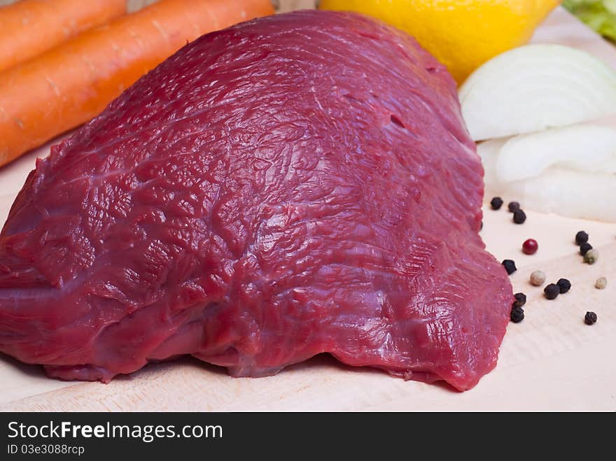 Fresh beef tenderloin and vegetables on cutting board, selective focus. Fresh beef tenderloin and vegetables on cutting board, selective focus.