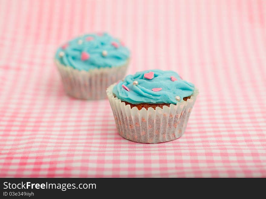 Delicious blue birthday cupcake against a pink background