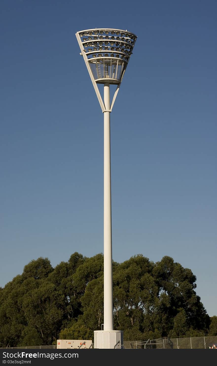 A tall floodlights stand against a blue sky background. A tall floodlights stand against a blue sky background