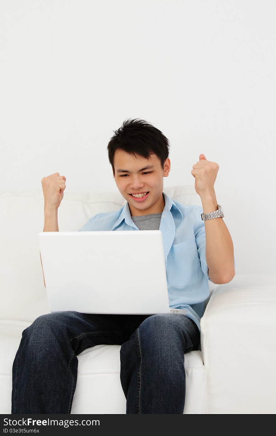 An excited Asian man with his laptop at home. An excited Asian man with his laptop at home