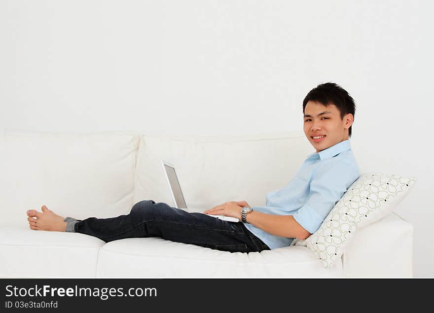 A man working with his laptop on a sofa. A man working with his laptop on a sofa