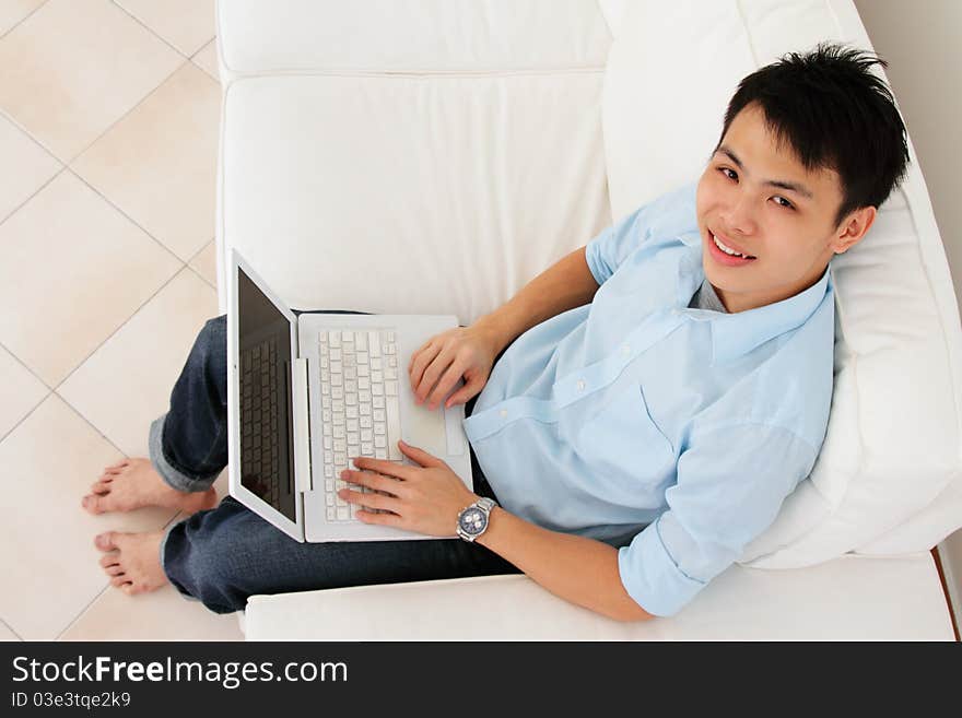 An Asian man working with his laptop at home. An Asian man working with his laptop at home