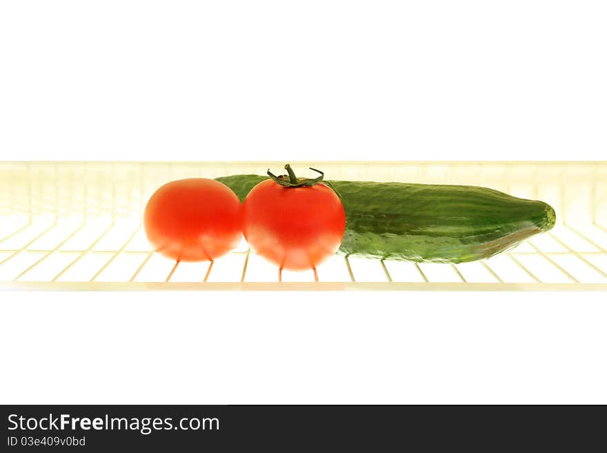 Rack with tomato and cucumber in the fridge. Rack with tomato and cucumber in the fridge.