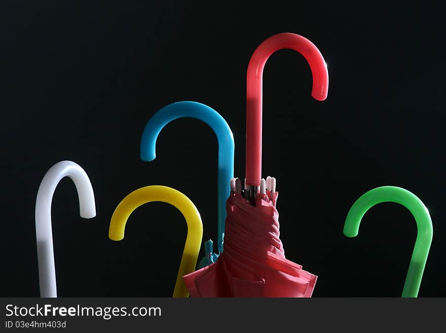 Very colourful nicely illuminated handles of the five umbrellas against the black background.