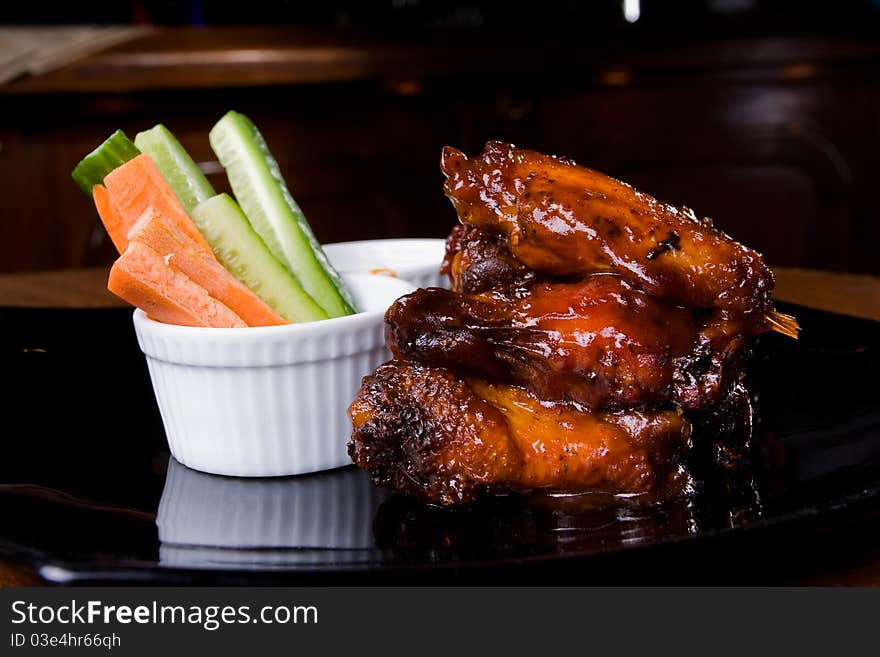 Chicken legs with some vegetables on a black porcelain plate