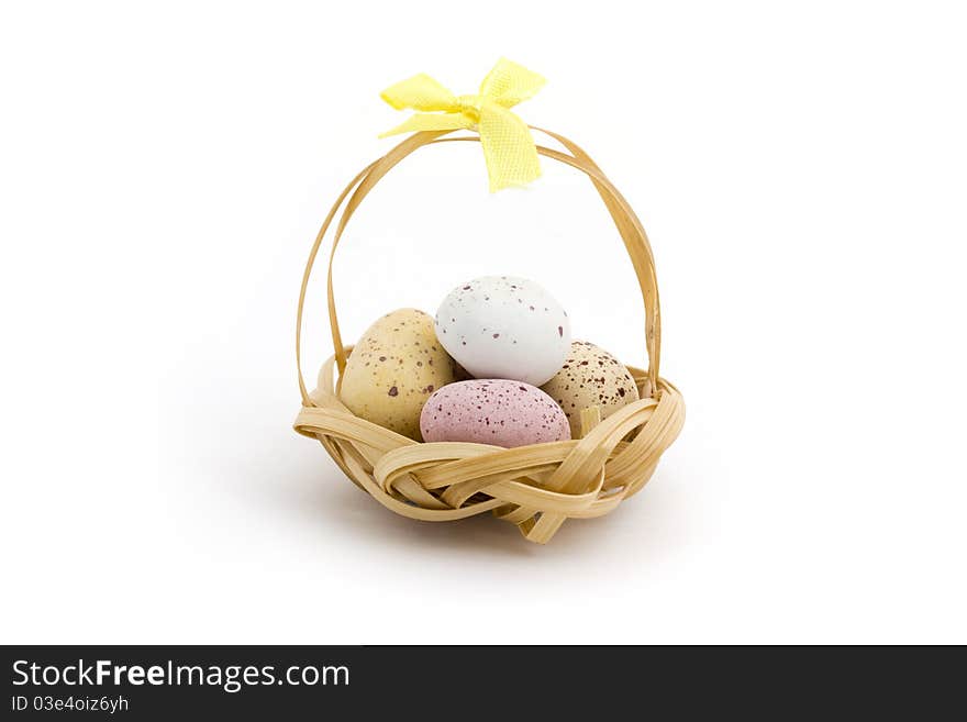 Basket of candy coated chocolate easter eggs over white