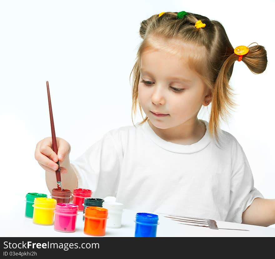 Cute little girl with a brush and paints