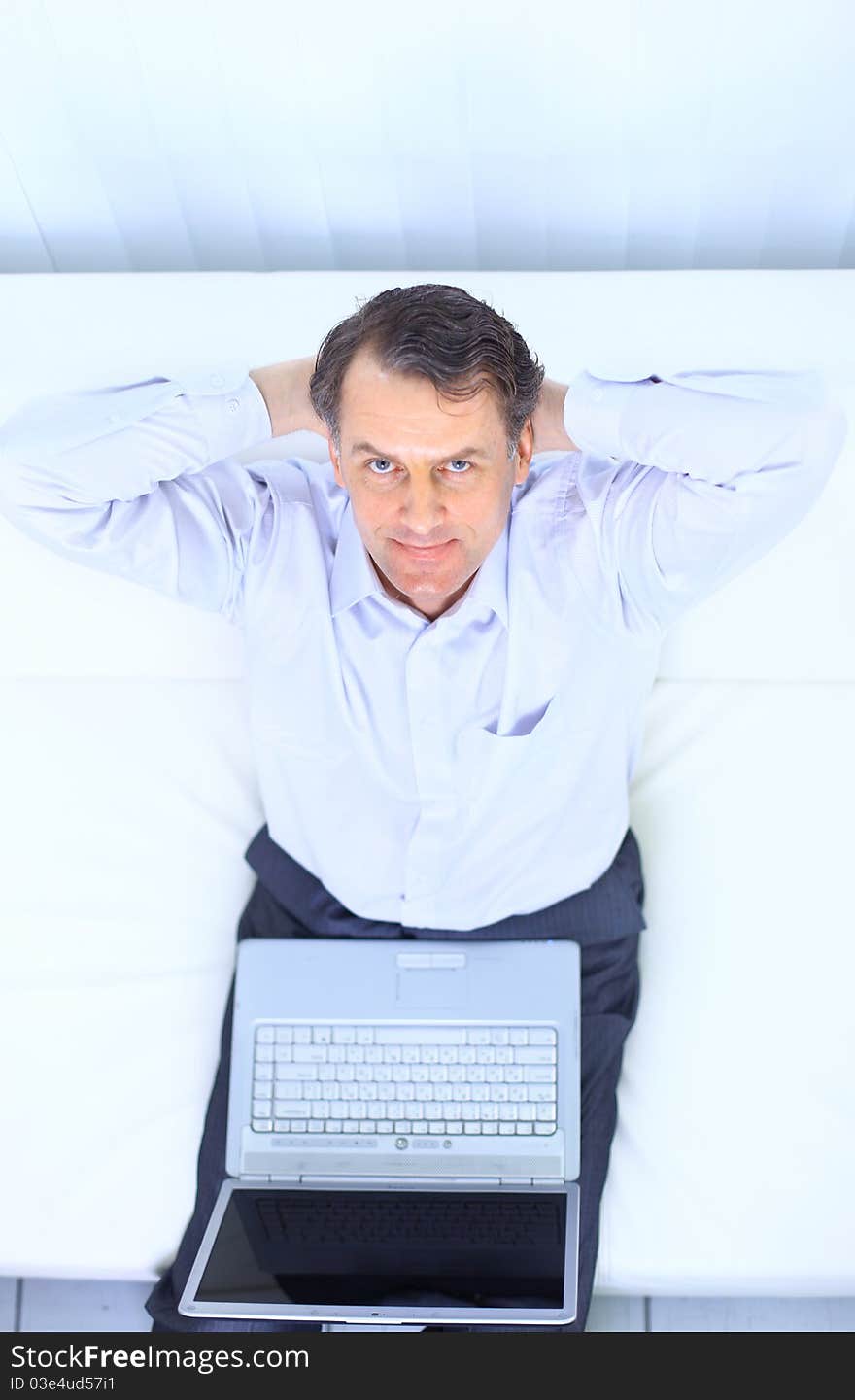 Entrepreneur working from home looking very relaxed in his sofa browsing the web in his laptop computer. Entrepreneur working from home looking very relaxed in his sofa browsing the web in his laptop computer