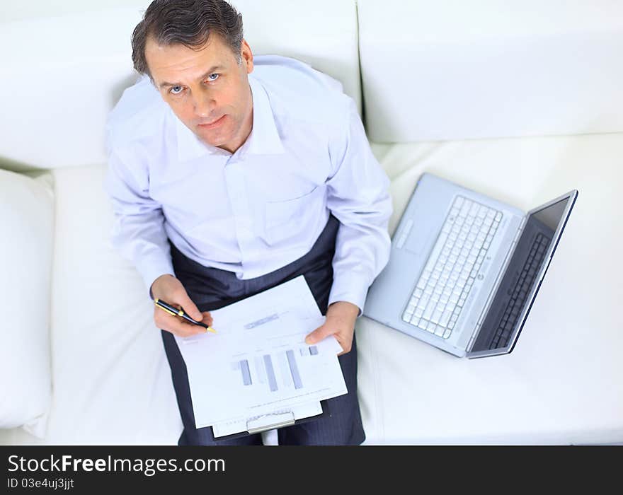 Entrepreneur working from home looking very relaxed in his sofa browsing the web in his laptop computer. Entrepreneur working from home looking very relaxed in his sofa browsing the web in his laptop computer