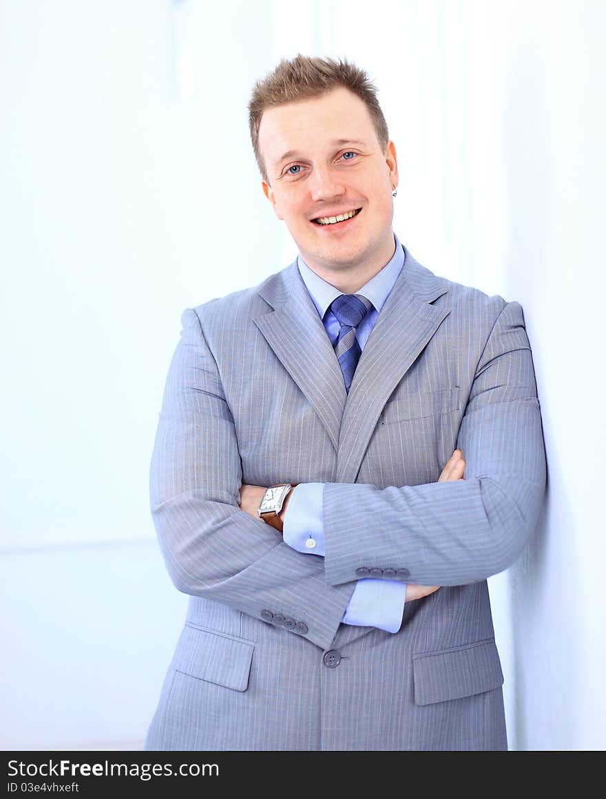 Full length of a handsome business man with hands folded against white background