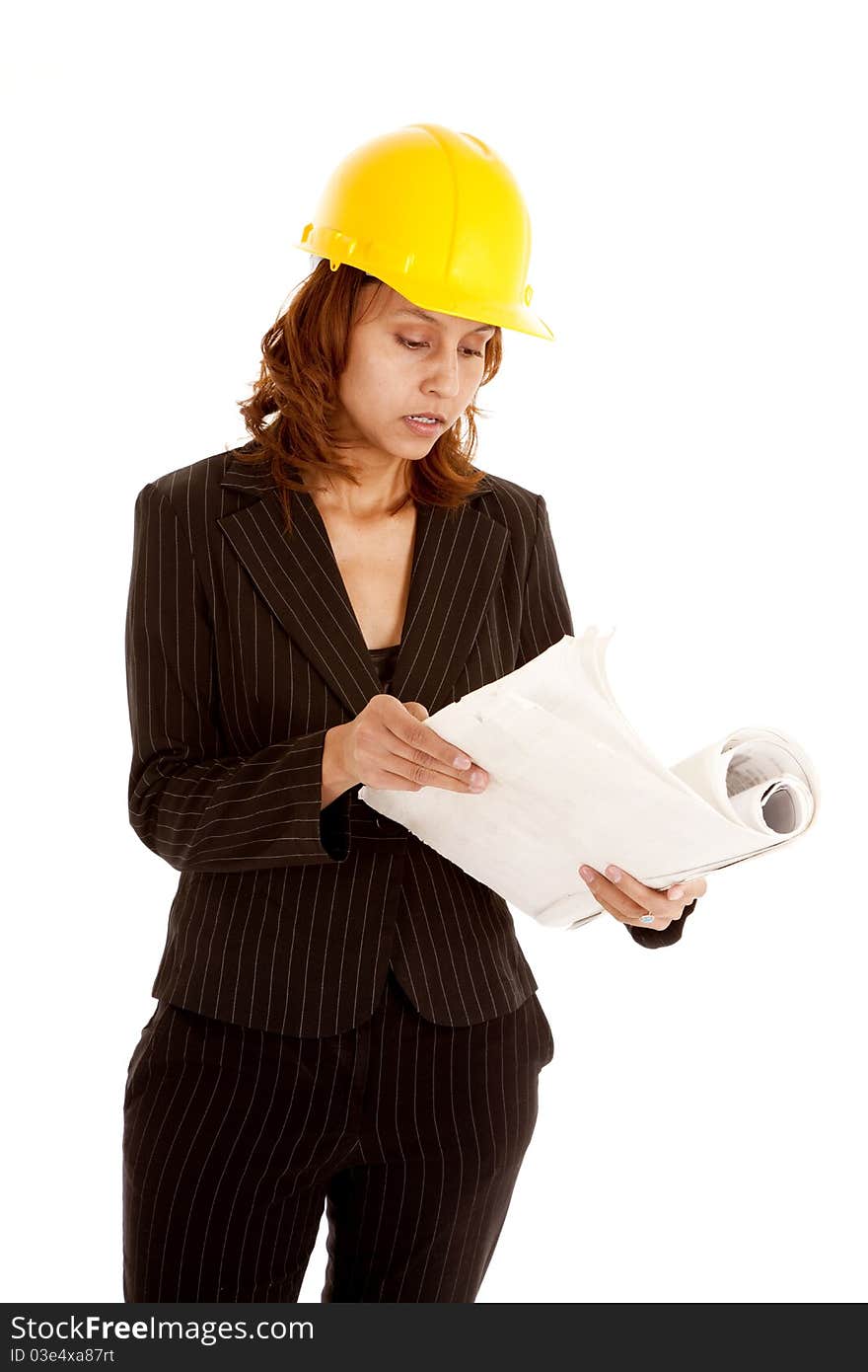 A woman is in a business suit and a hard hat looking at plans. A woman is in a business suit and a hard hat looking at plans.