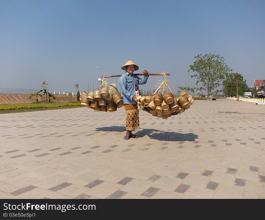 Traditional asian sale on the street, woman with baskets in Laos