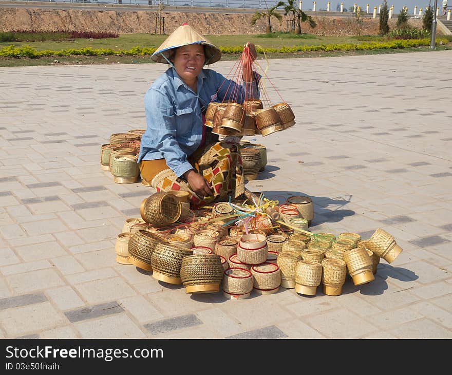 Traditional asian sale on the street, woman with baskets in Laos