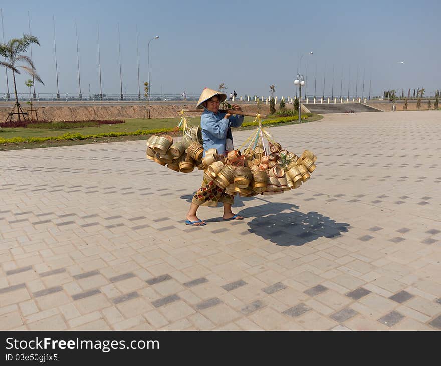 Traditional asian sale on the street, woman with baskets in Laos