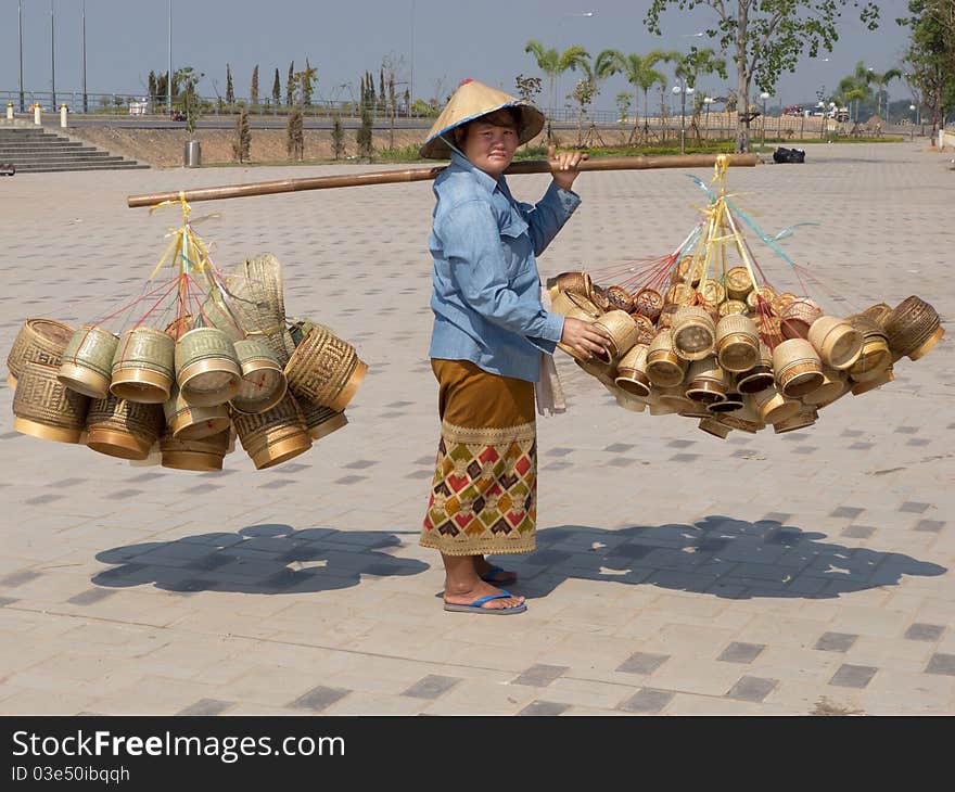 Traditional asian sale on the street, woman with baskets in Laos