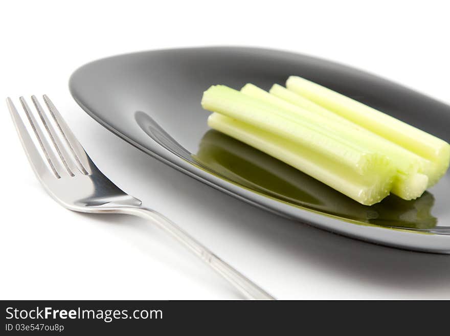 Green celery on black plate with fork. Green celery on black plate with fork