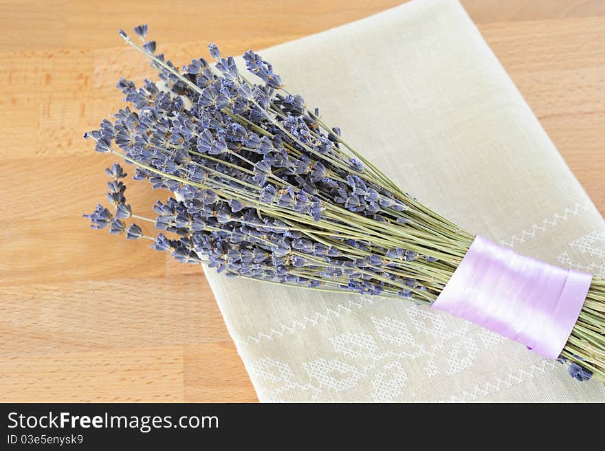 Dried lavender, tied with purple ribbon, with a linen cloth on a wooden table