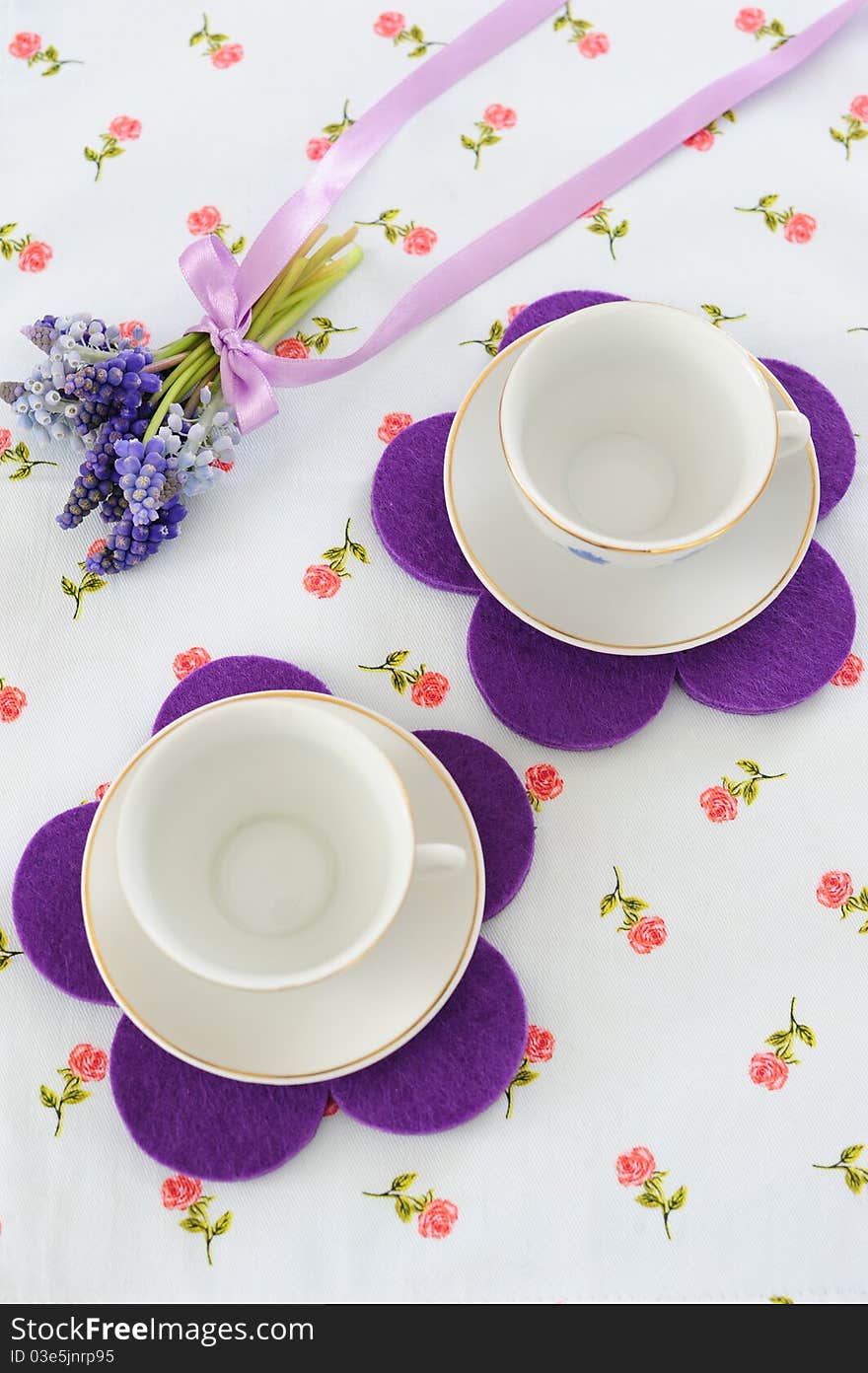 Two cups with a bouquet of muscari on colored tablecloths. Two cups with a bouquet of muscari on colored tablecloths