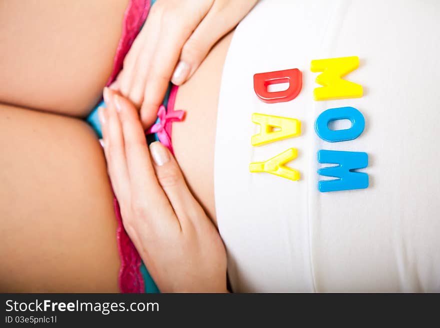 Pregnant woman belly with baby clothes