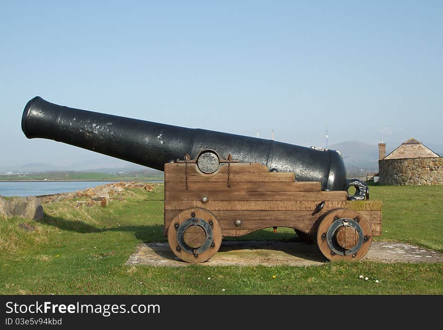 Historic cannon with a black barrel on a wooden trolley with wheels. Historic cannon with a black barrel on a wooden trolley with wheels.