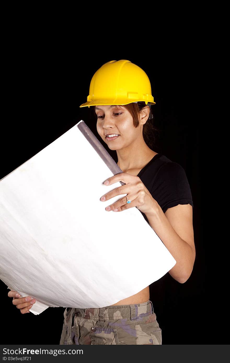 A woman in a yellow hard had is looking at some plans. A woman in a yellow hard had is looking at some plans.