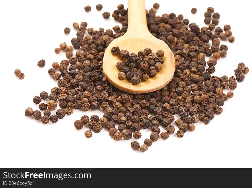 Black Peppercorns on a wooden spoon on white