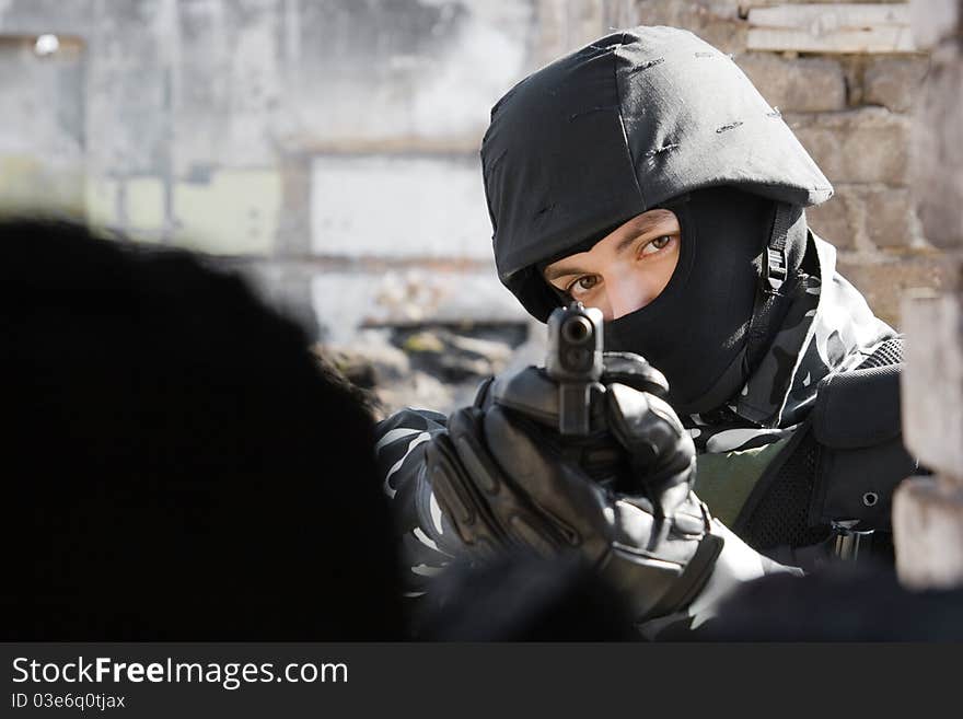 Man in black mask and bulletproof helmet pointing with a 9mm gun in the camera. Man in black mask and bulletproof helmet pointing with a 9mm gun in the camera