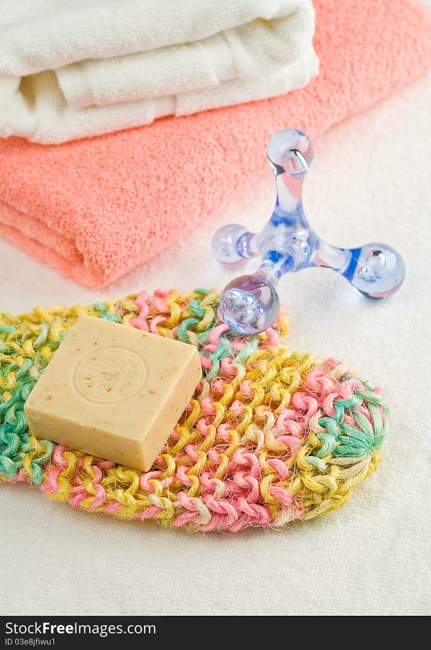 Studio shot cotton towels and natural bast with soap and massager on white cooton fabric. Studio shot cotton towels and natural bast with soap and massager on white cooton fabric