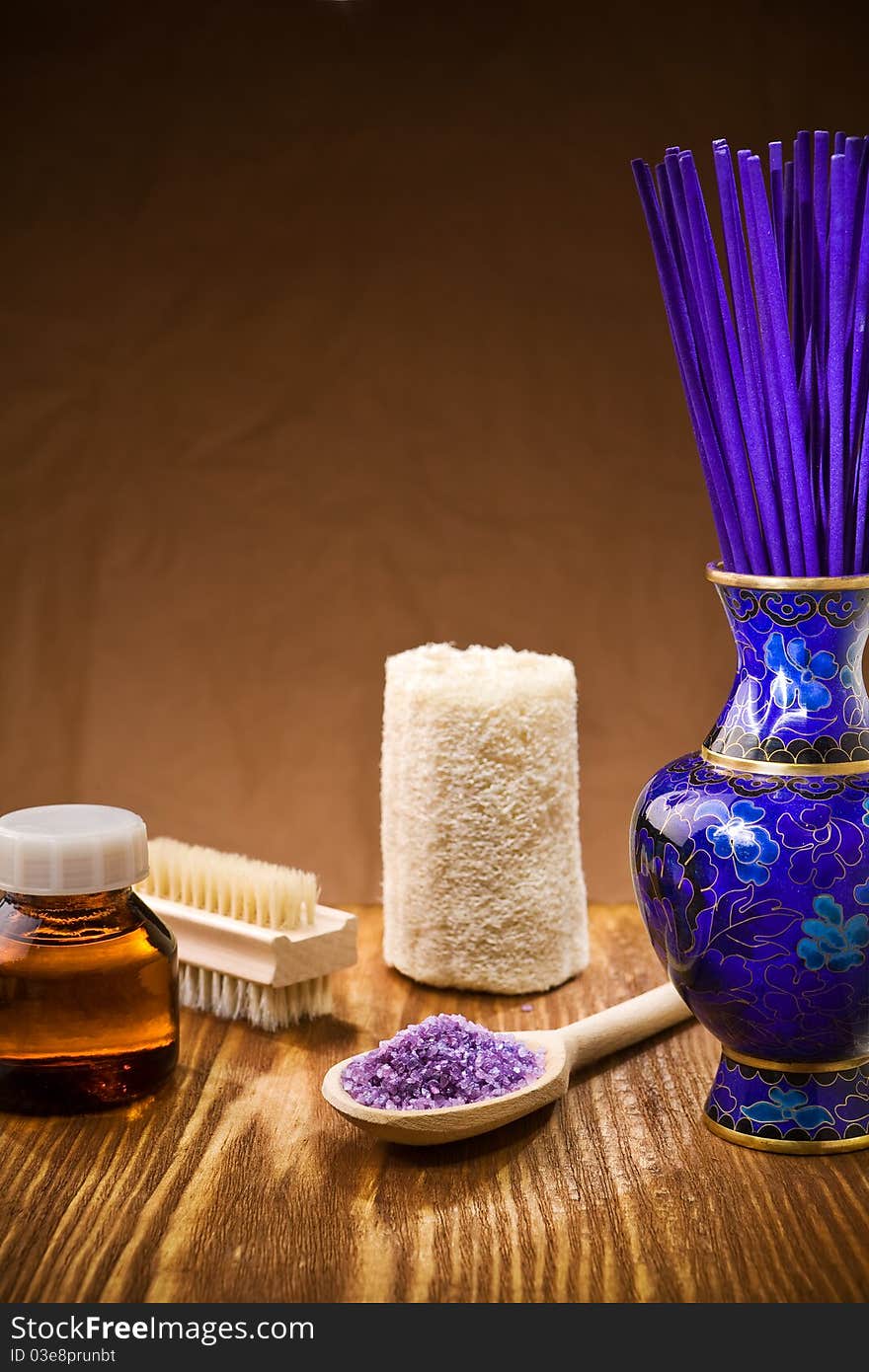 Studio shot copy space view on the spa accessories on wooden board and brown background vase with aroma stick wooden spoon with sea salt amber glass jar with oil brush loofah. Studio shot copy space view on the spa accessories on wooden board and brown background vase with aroma stick wooden spoon with sea salt amber glass jar with oil brush loofah