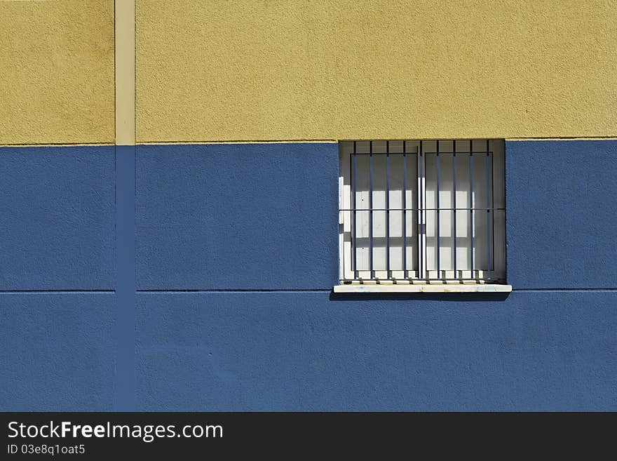 Closed window with bars in a blue and yellow wall in Malaga, Spain. Closed window with bars in a blue and yellow wall in Malaga, Spain