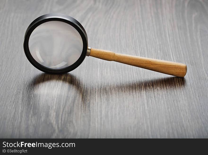 Studio shot  single magnifying glass on wooden boards