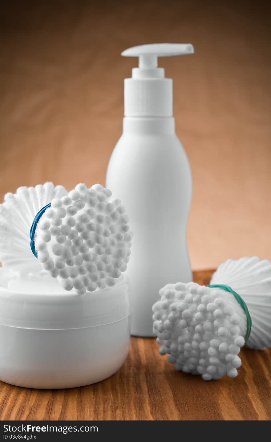 Studio shot two bunches of cotton swabs and bottle and jar on wooden boards