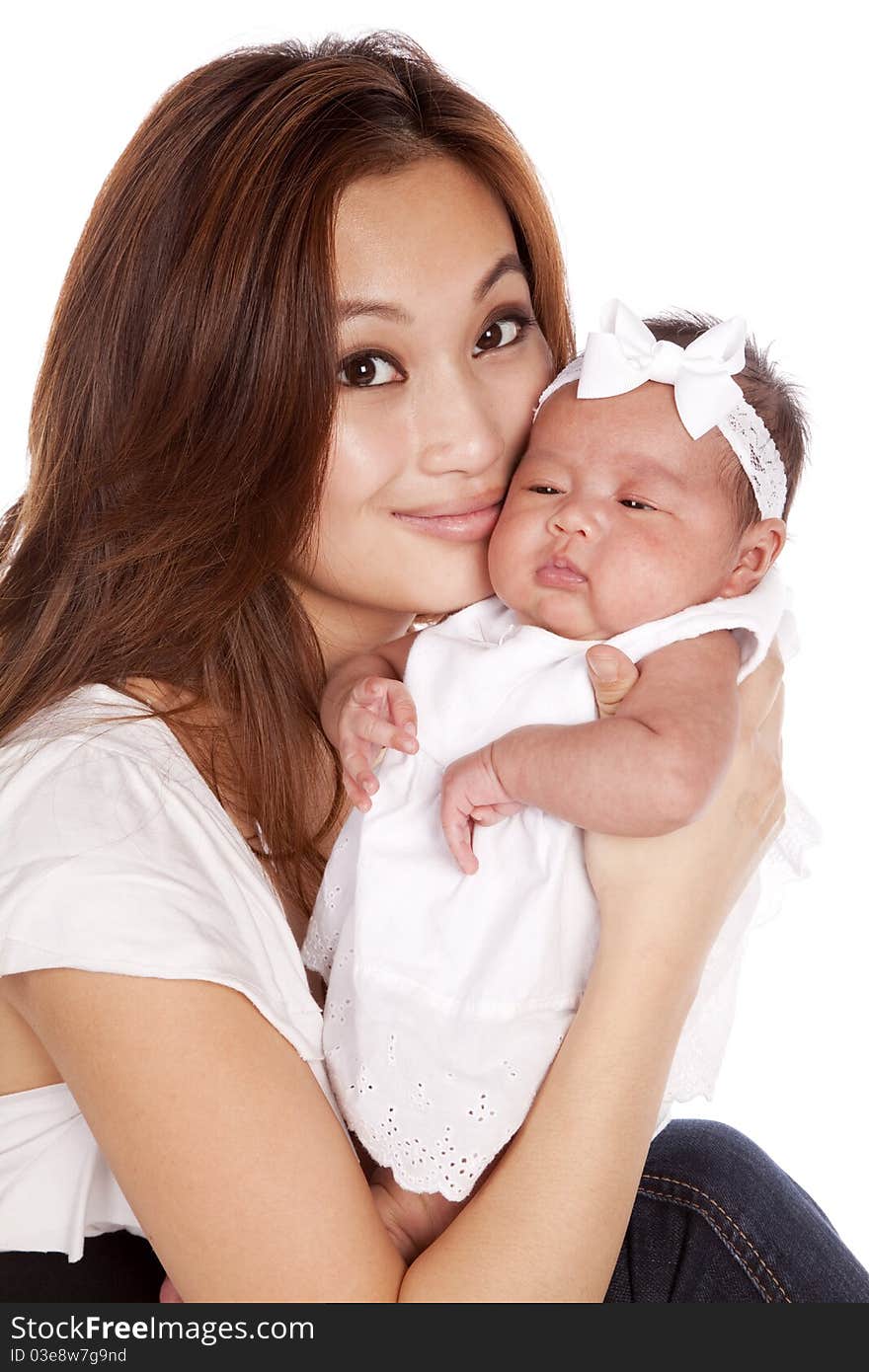 A oriental mother holding her beautiful daughter in her arms putting her lips next to her cheek. A oriental mother holding her beautiful daughter in her arms putting her lips next to her cheek.