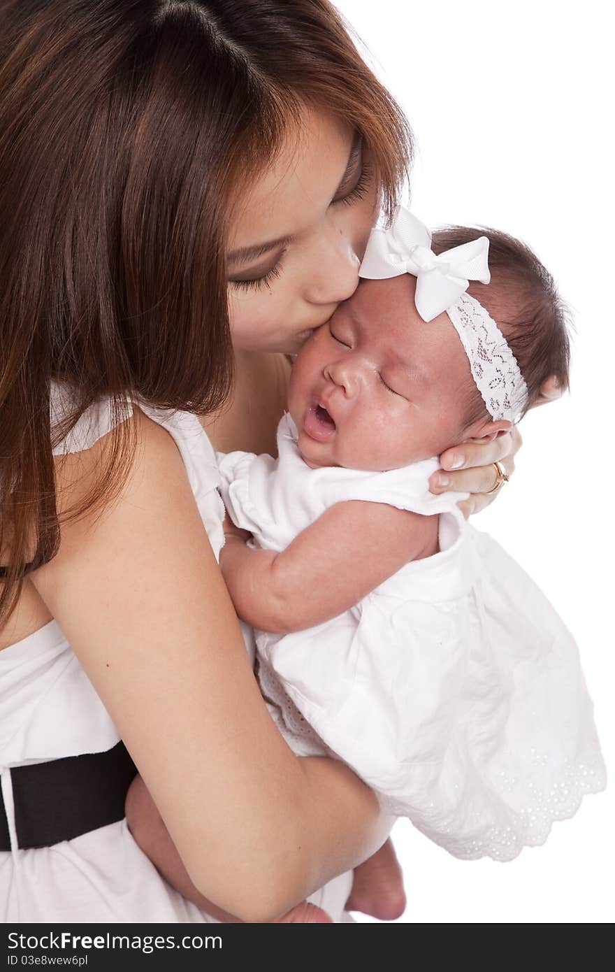 A oriental mother holding her beautiful daughter in her arms kissing her head. A oriental mother holding her beautiful daughter in her arms kissing her head.