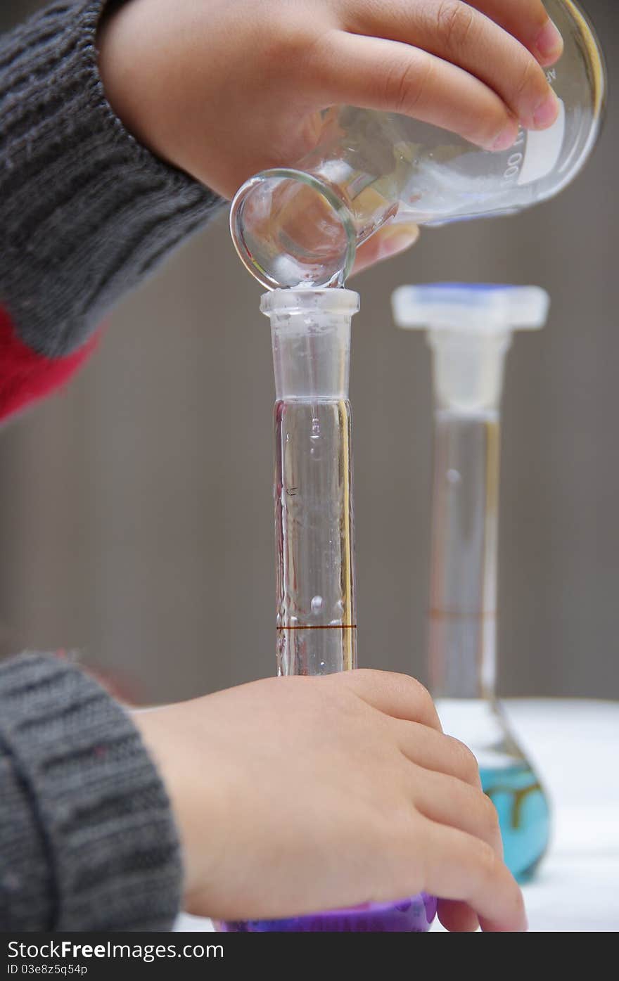 Child's hands are holding a tube to drop the liquid. Child's hands are holding a tube to drop the liquid