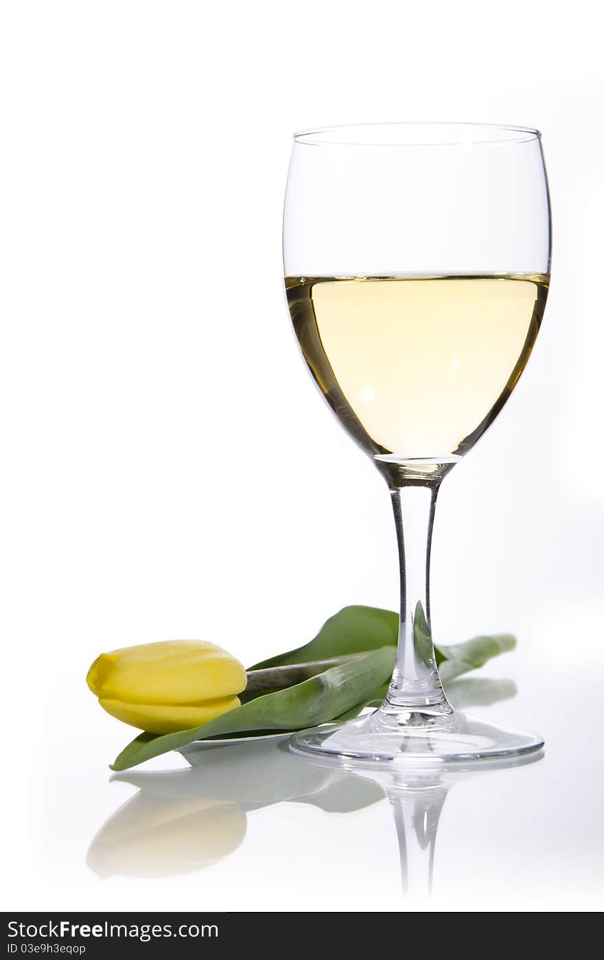 Glass of white wine and yellow tulip on a white background. Glass of white wine and yellow tulip on a white background