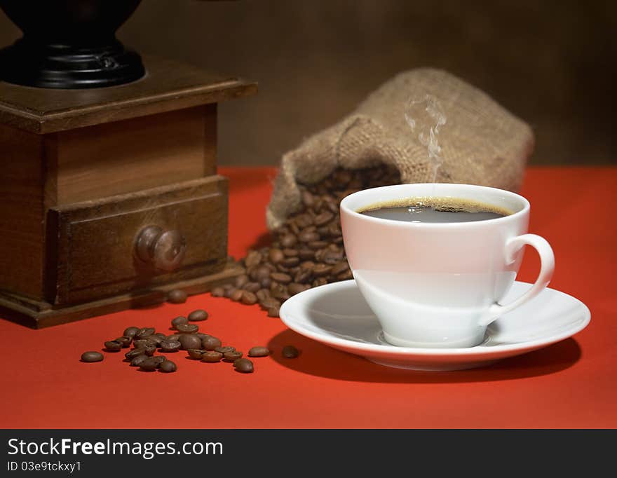 Coffee grinder, a cup of coffee, a bag of coffee beans on the table