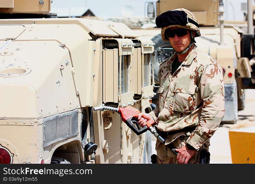 A soldier with helmet and uniform refueling military tactical vehicle outdoor. A soldier with helmet and uniform refueling military tactical vehicle outdoor