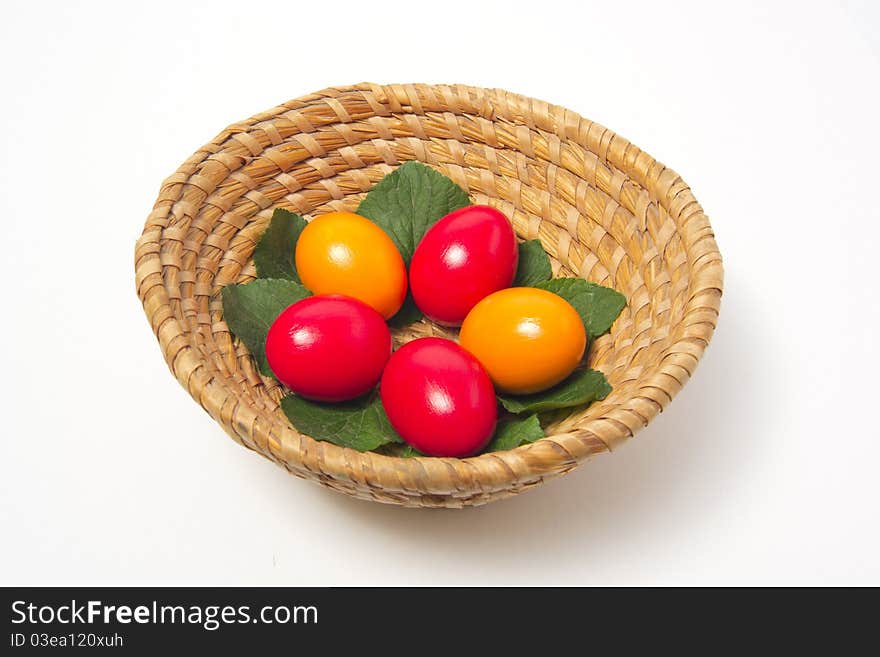 Red and yellow eggs on leaf in basket. Red and yellow eggs on leaf in basket