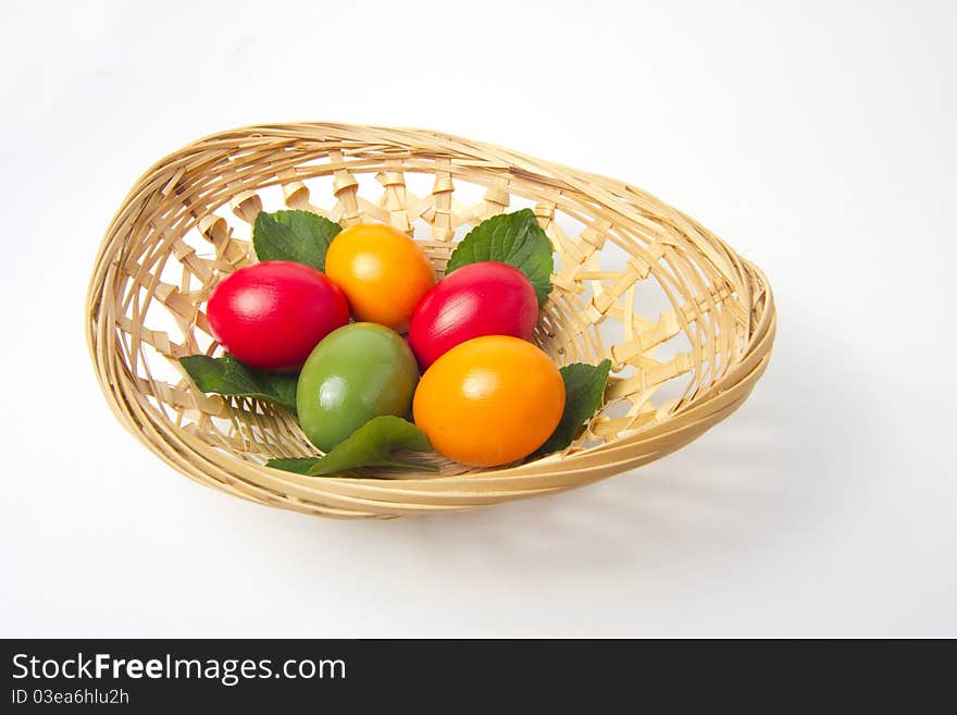 Five colored eggs on leafs in a basket on white background. Five colored eggs on leafs in a basket on white background