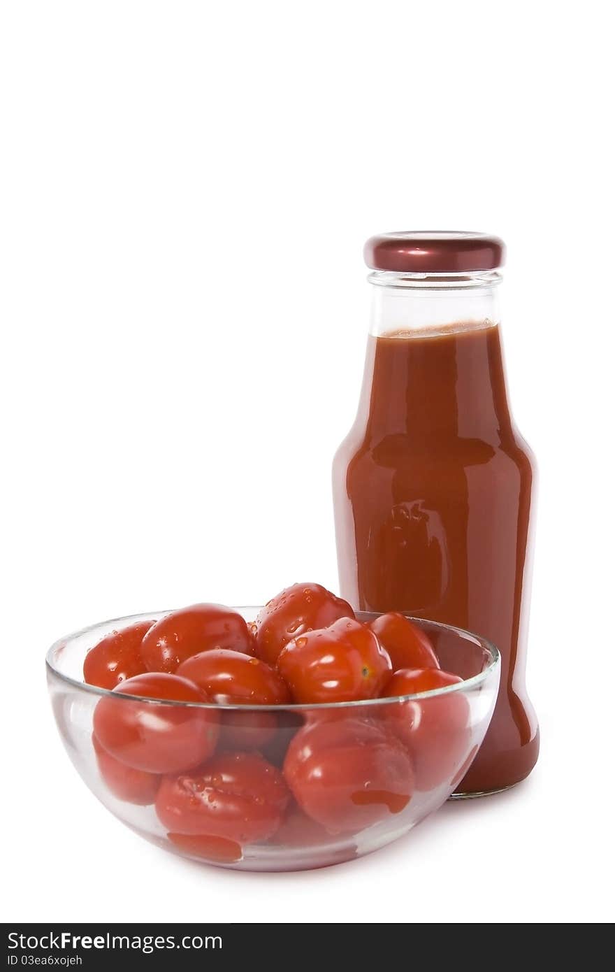 Red cherry tomatoes in a glass bowl with a bottle of ketchup isolated on white. Red cherry tomatoes in a glass bowl with a bottle of ketchup isolated on white