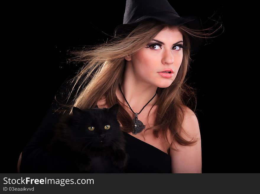 Beautiful girl dressed as a witch holding cat