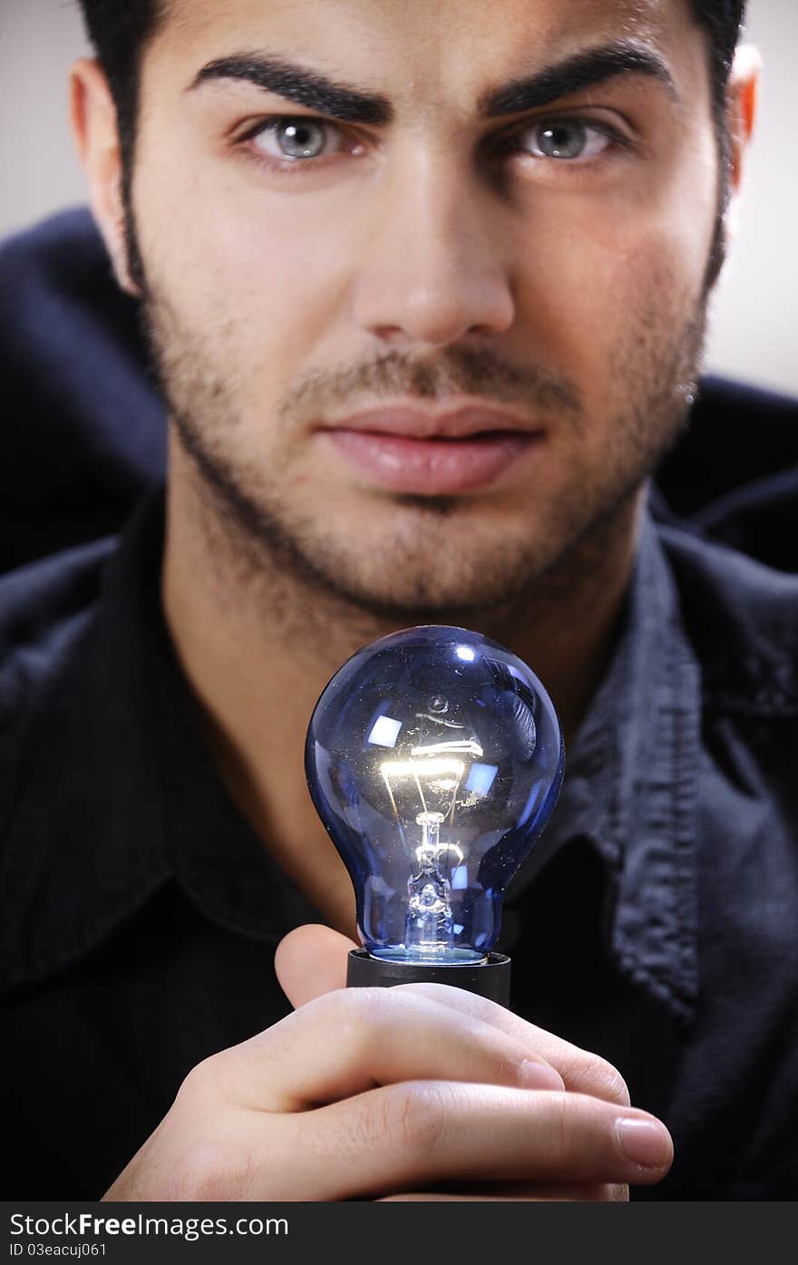 Young man with light bulb in his hands and looking in camera