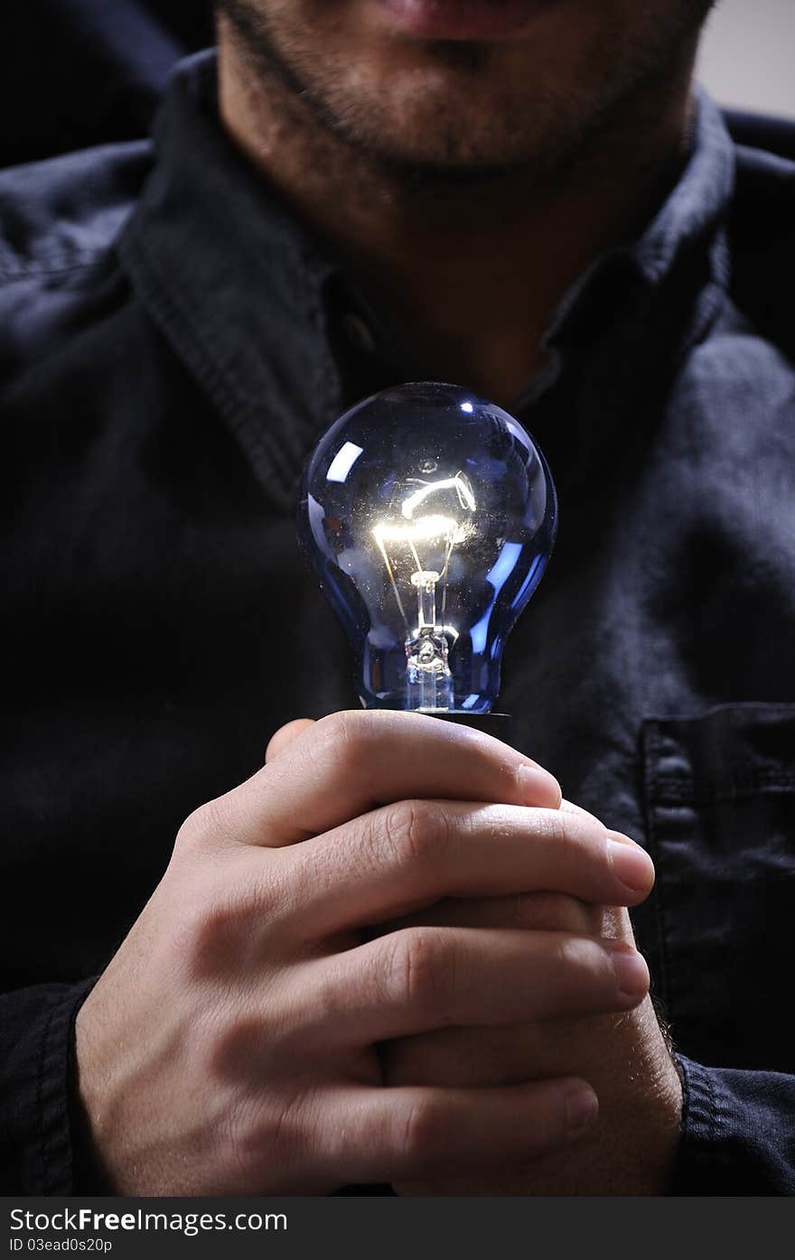 Young man with light bulb in his hands and looking in camera