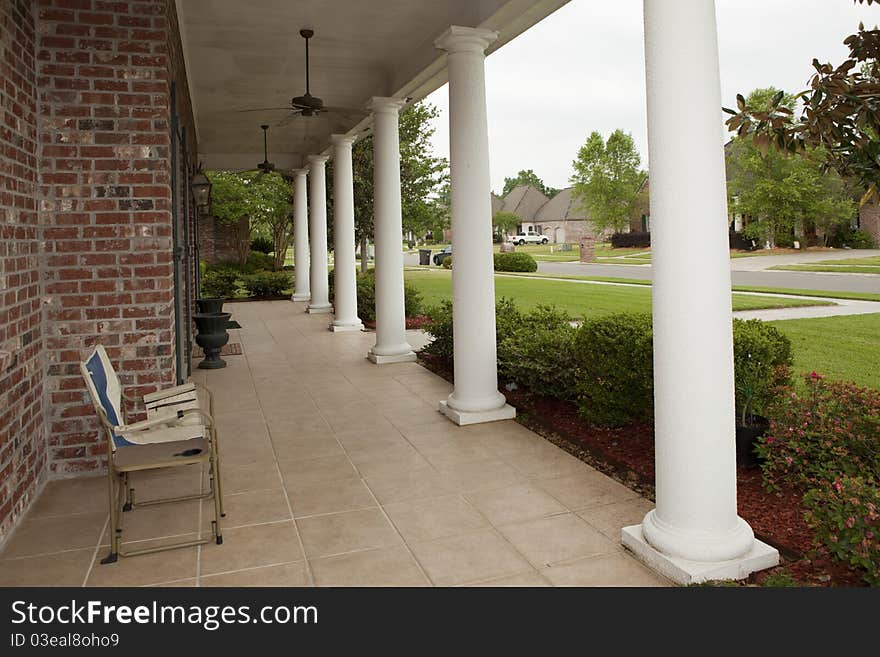 Angular view of front porch with white columns and ceiling fans overhead