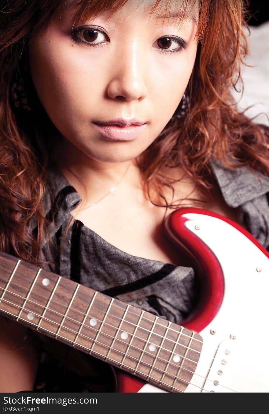 Young asian woman with a red guitar. Young asian woman with a red guitar.