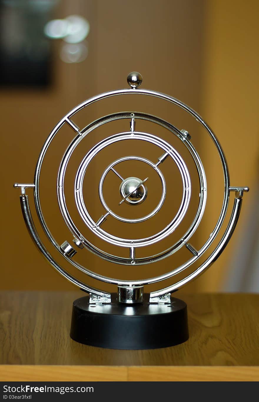 Swinging pendulum on the table in the room