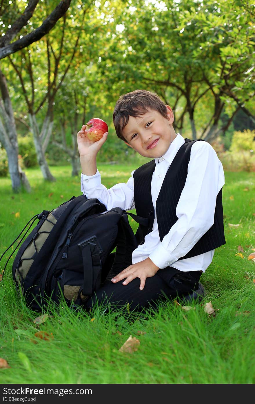 Schoolboy with backpack and apple outdoors