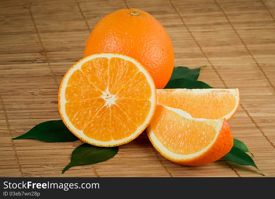 Fresh orange with segments and leaves on a mat. Fresh orange with segments and leaves on a mat