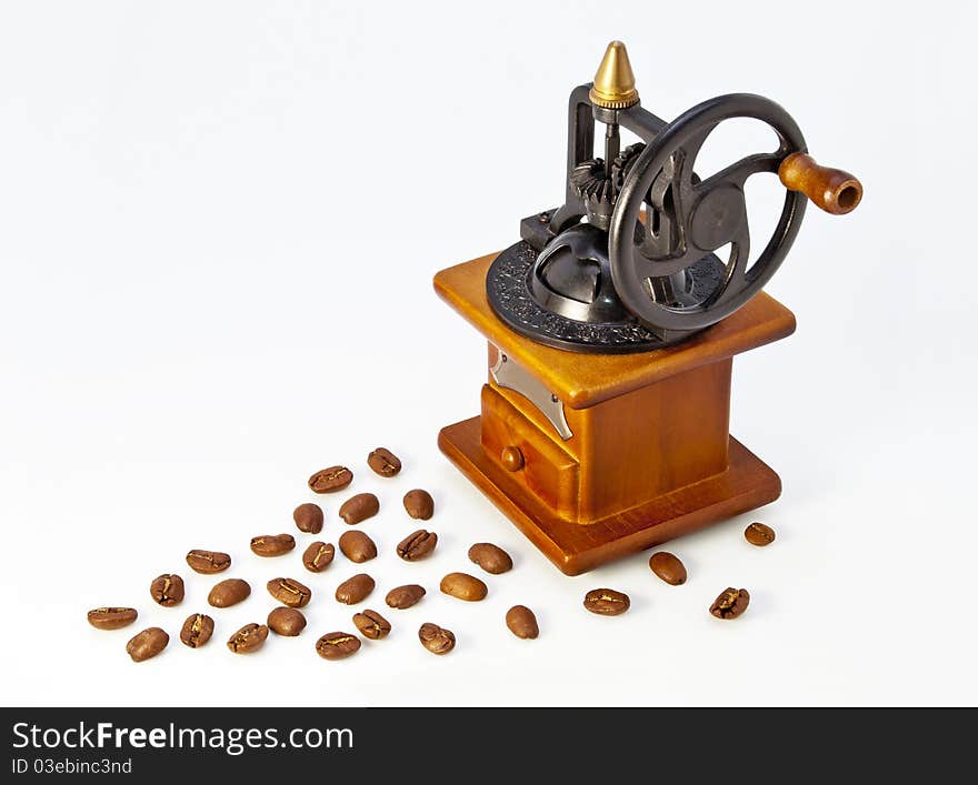 Antique wooden coffee grinder with a white background with spilled coffee. Antique wooden coffee grinder with a white background with spilled coffee.